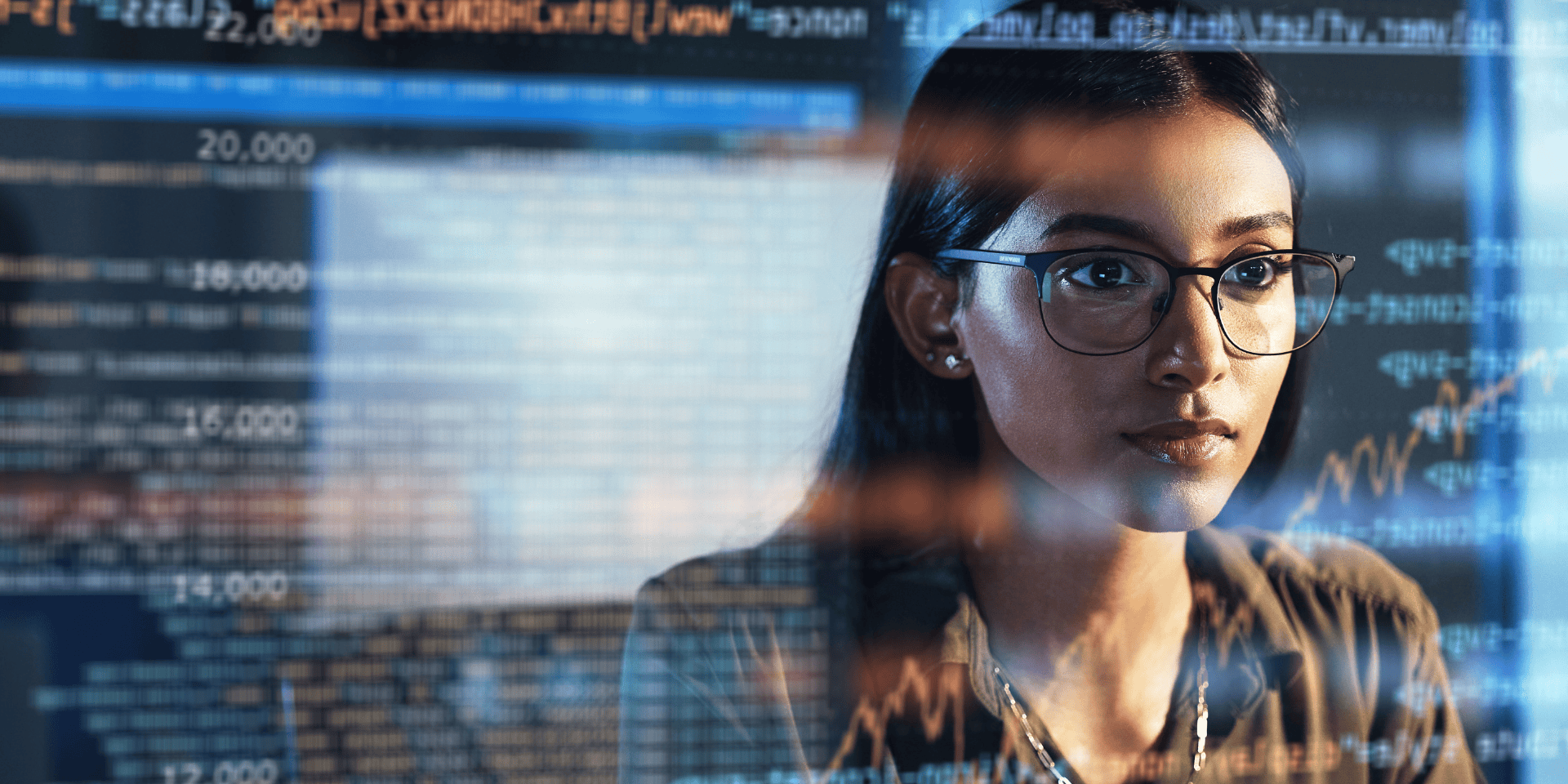 Focused woman in glasses analysing data on screen, representing women in tech roles and challenges highlighted in the Lovelace Report 2025.